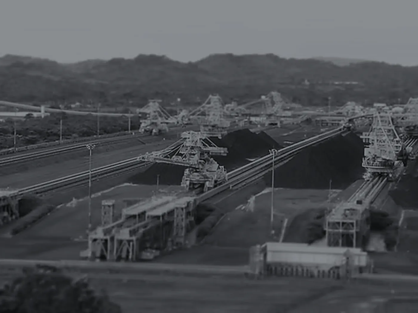 Pátio de estocagem de minério com máquinas de pátio em carga, imagem em duotone grafite