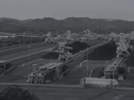 Pátio de estocagem de minério com máquinas em carga, em duotone grafite, do segmento de mineração